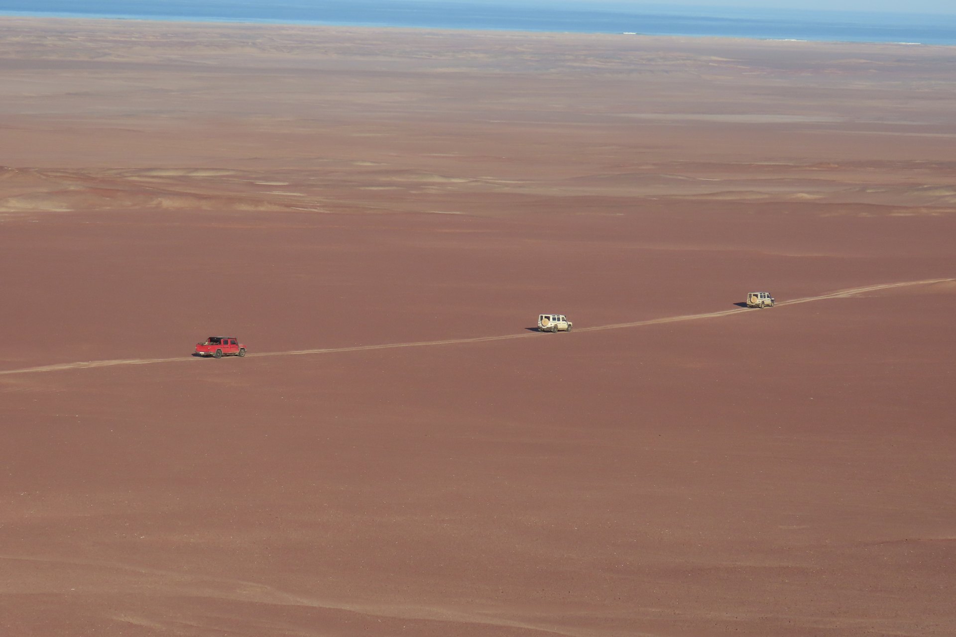 Vehicles crossing the open Skeleton Coast landscape